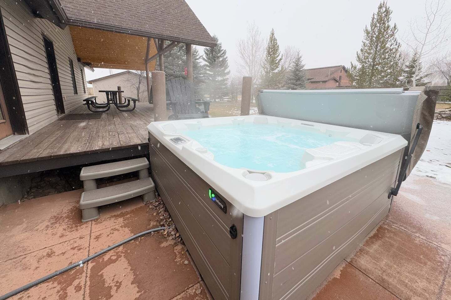 Un jacuzzi con terraza de madera y escalones que lo llevan.