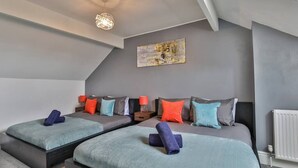 Une chambre moderne avec deux lits, des murs gris et un luminaire au plafond.