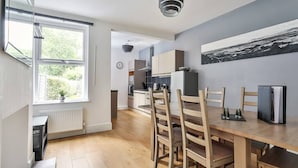 Une cuisine moderne avec un coin repas, des chaises en bois, une grande fenêtre et un tableau en noir et blanc accroché au mur.