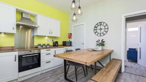 A modern kitchen with white cabinets, a stainless steel range hood, and a wooden dining table with benches. - ★Heart of the City★Totally Upgraded ✔ Sleeps 10 (Sheffield)