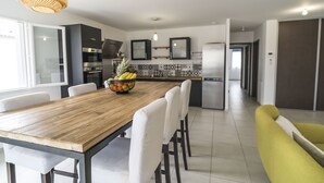 Een moderne keuken met een houten eettafel, witte stoelen en een fruitschaal.