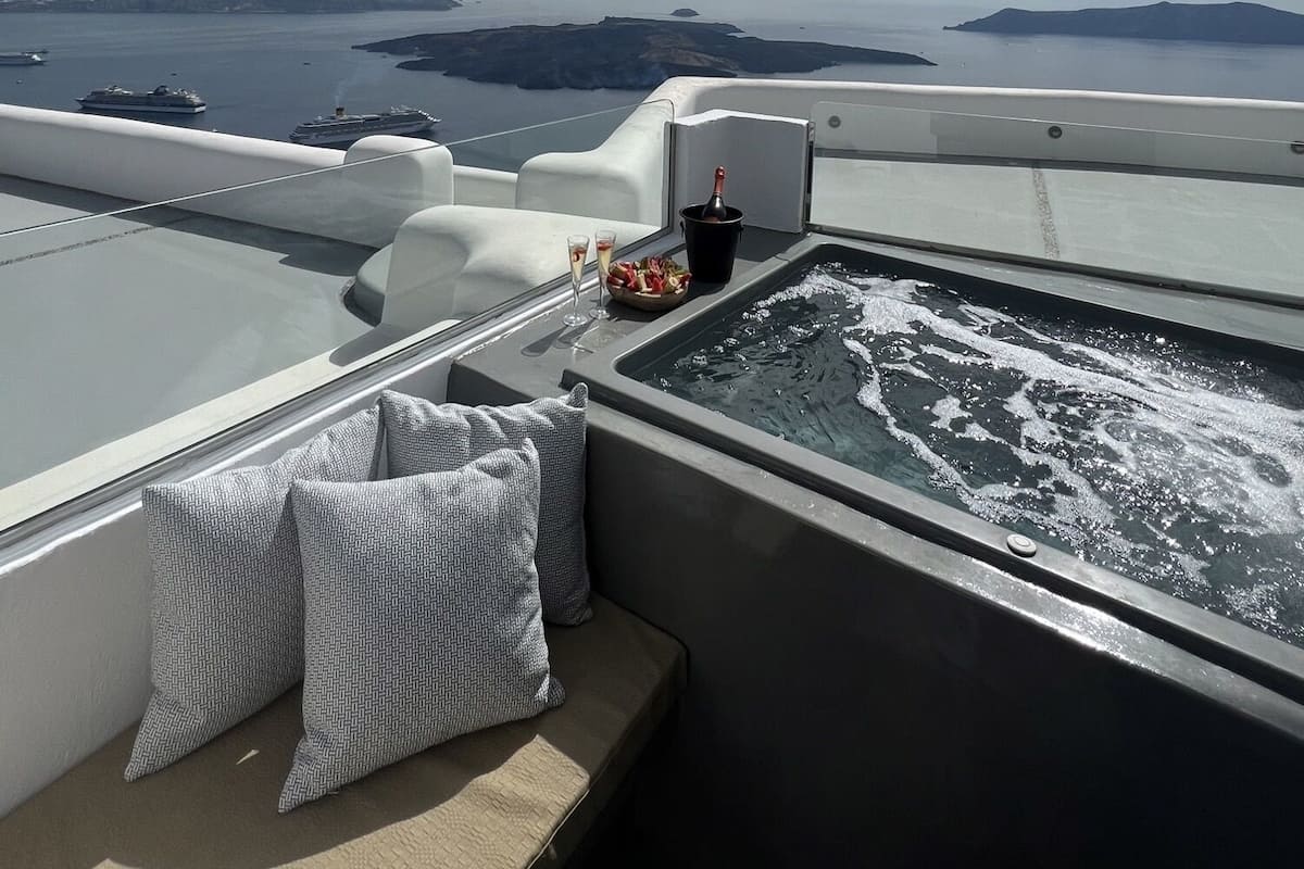 A luxurious boat deck with a hot tub, seating area, and a view of the sea and islands.