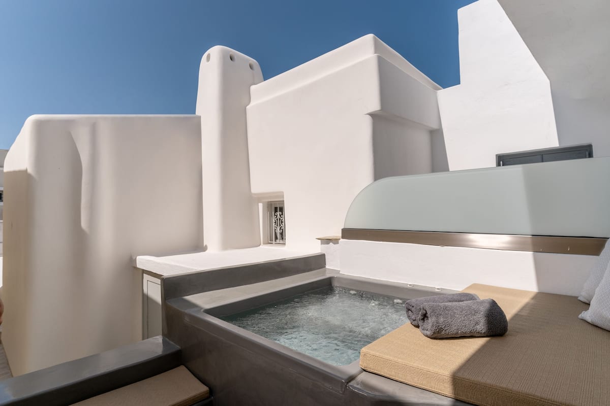 A modern, minimalist bathroom with a bathtub, a towel, and a bench.