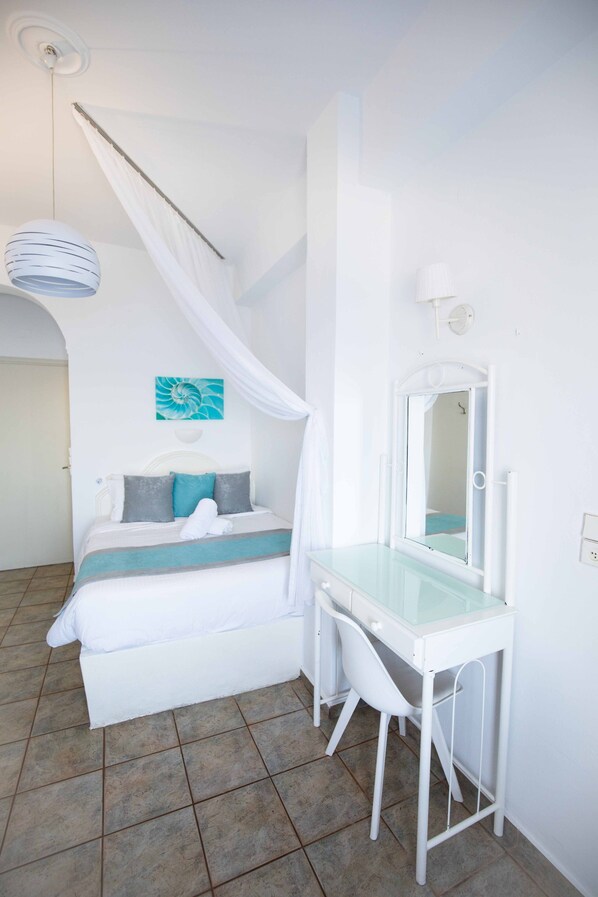 Une chambre à coucher avec un lit, une coiffeuse avec un miroir et un ventilateur de plafond.