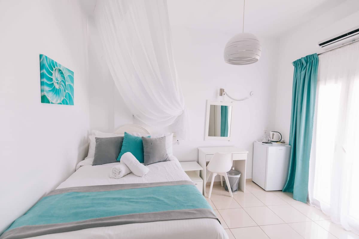 A modern bedroom with a bed, a desk, a chair, and an air conditioning unit.