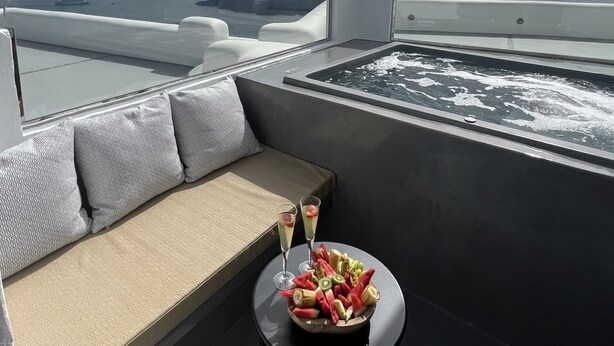 Una terraza en la azotea con zona de estar, jacuzzi y una mesa con fruta y bebidas.