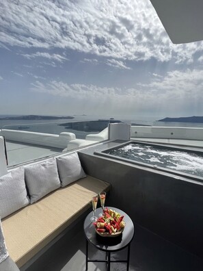 A rooftop terrace with a seating area, a hot tub, and a table with fruit and drinks. - Kafieris View Hotel - Adults Only (Santorini)
