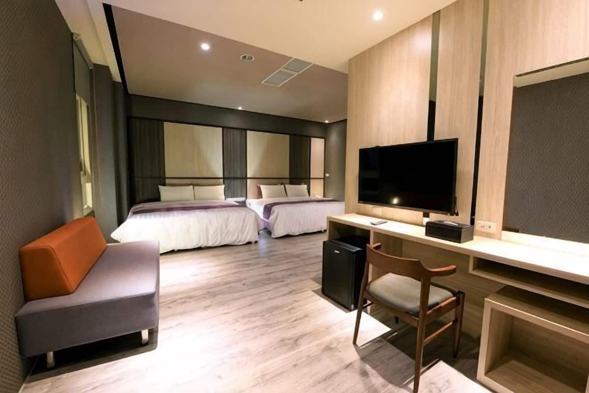 Ein modernes Hotelzimmer mit Bett, Schreibtisch, Fernseher und Sitzecke.