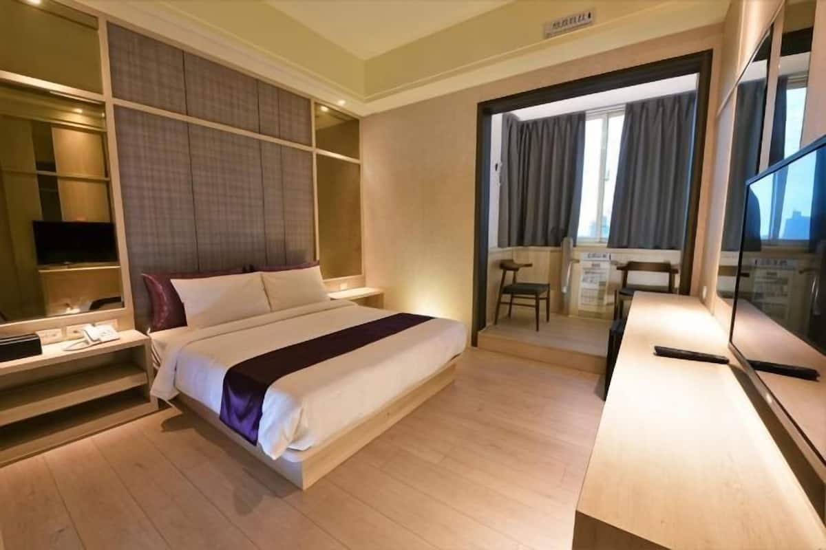Ein Hotelzimmer mit einem großen Bett, einem Schreibtisch, einem Fernseher und einem Balkon mit Aussicht.