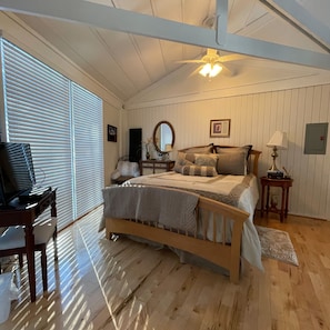 Cozy bedroom with a wooden bed, sloped ceiling, and ceiling fan.