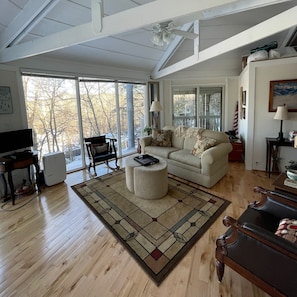 Relax in this open living room with a high ceiling, floor-to-ceiling windows, and a comfortable sofa.