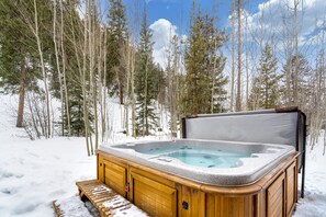 Relax in a secluded hot tub surrounded by snow-covered trees and a serene forest landscape.