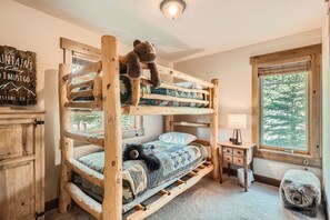 Sleep comfortably in this cozy room with a multi-level bunk bed and a bedside table.
