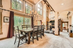 Enjoy meals in this dining area with a large table and six chairs, surrounded by high ceilings and large windows.