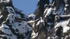 Ein schneegebdeckter Berg mit einer Brücke und einem Geländer.