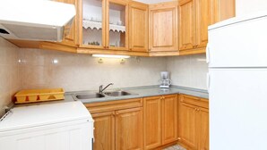 A compact kitchen with wooden cabinets, a double sink, a coffee maker, and a white refrigerator. - Lovely 2-bedroom Apartment in Poljica (Marina)