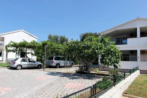 Un barrio residencial con edificios de dos pisos, un camino de entrada pavimentado y automóviles estacionados.