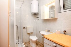 Un baño con ducha, inodoro, lavamanos y un perchero para toallas.