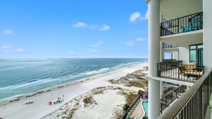 Ett hotell vid stranden med en pool, flera balkonger och utsikt över havet.