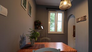 A dining area with a table, chairs, a potted plant, a window, and a wall-mounted sign. - Art Apartment Nearby the sea (Dubrovnik)