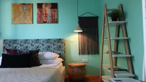 A bedroom with a bed, a wall-mounted shelf with a plant, a woven basket, and a ladder shelf. - Art Apartment Nearby the sea (Dubrovnik)
