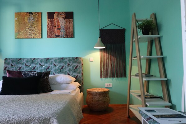 A bedroom with a bed, a wall-mounted shelf with a plant, a woven basket, and a ladder shelf. - Art Apartment Nearby the sea (Dubrovnik)