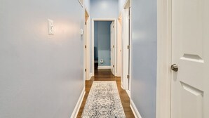 Un couloir étroit aux murs bleu clair, doté d’un plancher en bois et orné d’un tapis à motifs.