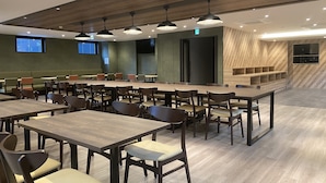 A spacious dining area with multiple tables and chairs, wooden ceiling, and green walls. - Smile Hotel Shinosaka (Osaka)