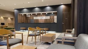 A modern hotel lobby with wooden furniture, a reception desk, and a wall-mounted sign reading "Smile Hotel". - Smile Hotel Shinosaka (Osaka)