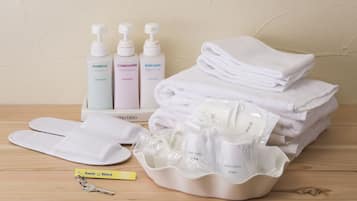 A hotel room with a neatly arranged bathroom area including toiletries, towels, and slippers.
