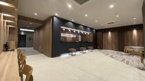 A spacious hotel lobby with a reception desk, seating area, and a large mirror wall. - Smile Hotel Shinosaka (Osaka)
