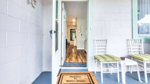 A hallway with a welcome mat, white walls, and a wooden floor leading to a room. - Entire House;  20 min to Beaches, Downtown Charleston, 6 min to Airport, Outlets (North Charleston)