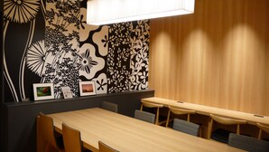 A conference room with a long table and chairs, a modern light fixture, and a decorative wall with black and white patterns. - First Cabin Kansai Airport (Izumisano)