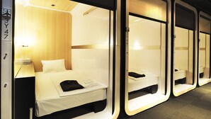 A hotel room with a bed, a nightstand, and a mirror. - First Cabin Kansai Airport (Izumisano)