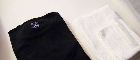 Una camisa negra bien doblada y una toalla blanca sobre la cama.