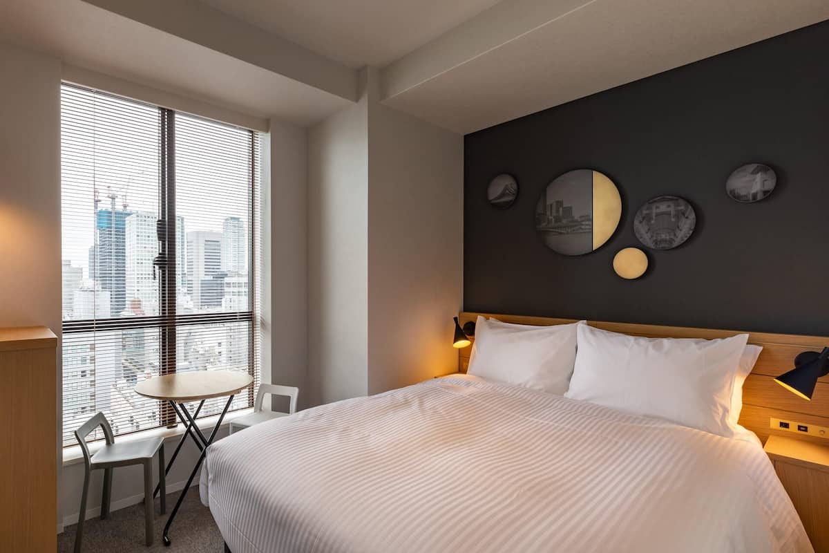 A modern hotel room with a large bed, a desk, and a chair.