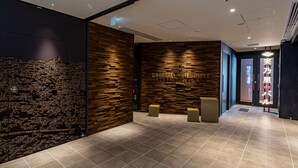 Un moderno hall de hotel con un diseño de pared de madera, una mesa de recepción y piso de baldosas.