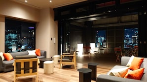 Una sala de estar moderna con vista a la ciudad, amoblada con sofás, sillones y una mesa de centro.
