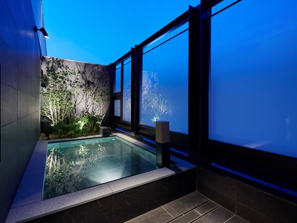 A modern indoor swimming pool with a view of trees through large windows.