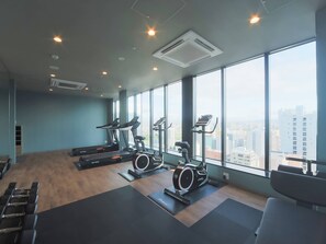 A gym with treadmills, elliptical machines, and stationary bikes, large windows with a city view, and a wooden floor. - Granbell Hotel Susukino (Sapporo)