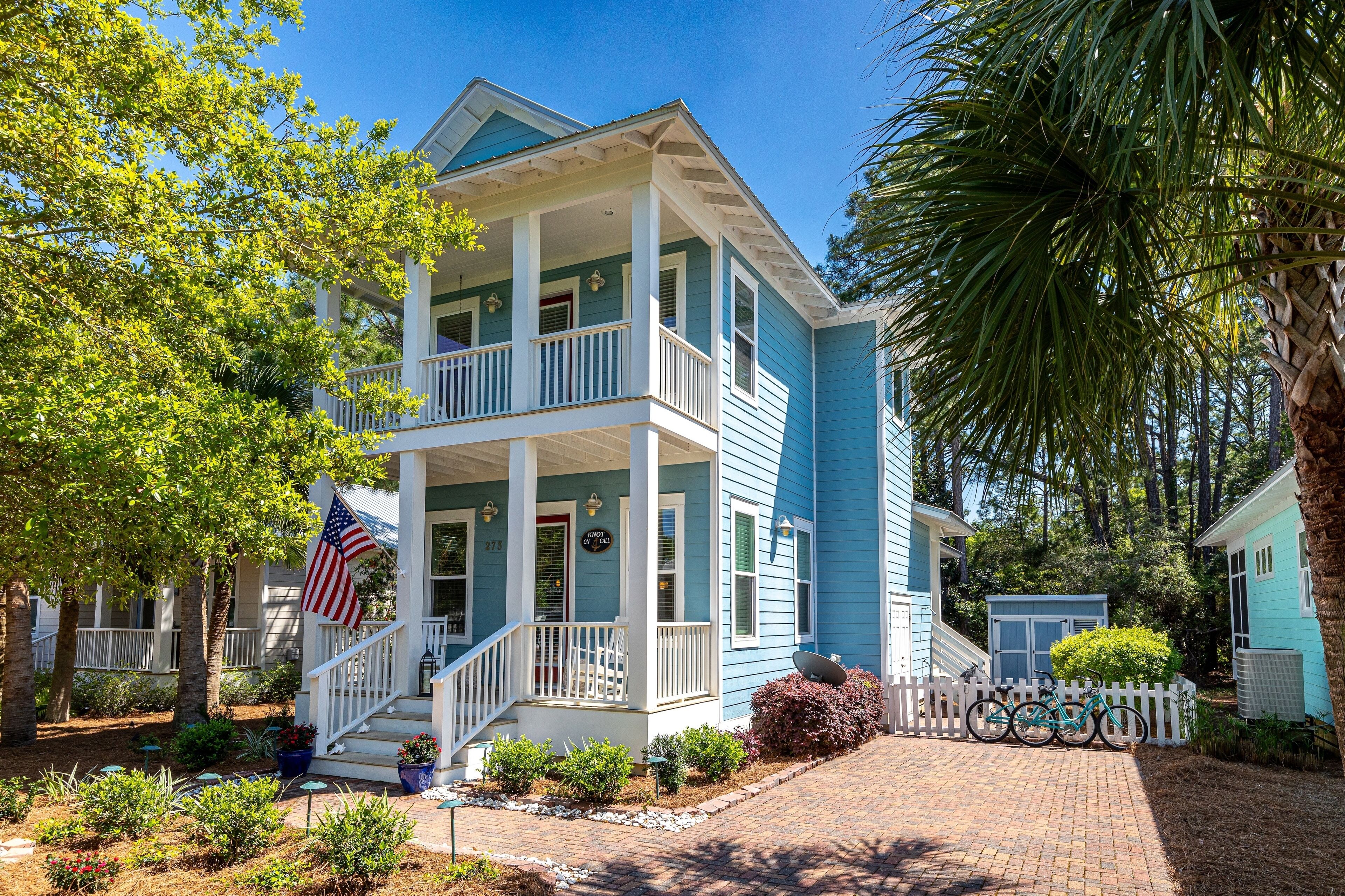 A two-story house with a porch, a flag, and a bicycle.