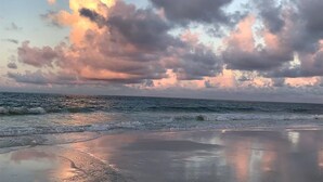 En strand med bølger og en overskyet himmel.