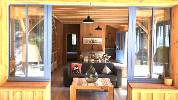 A wooden interior with a sofa, coffee table, and dining area.