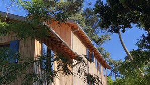 A wooden cabin with a sloped roof, large windows, and a staircase leading to the entrance.