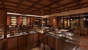 A modern hotel lobby with a bar area, seating, and a glass staircase.