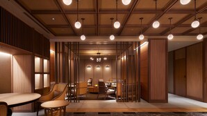 A modern hotel lobby with a wooden reception desk, seating area, and a dining space.
