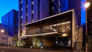 A modern hotel with a prominent entrance, a covered walkway, and a visible parking sign.