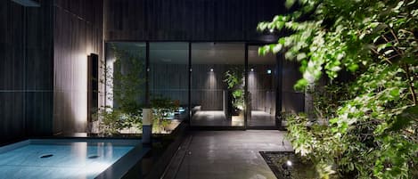 Un edificio moderno con entrada de cristal, piscina y zona ajardinada.