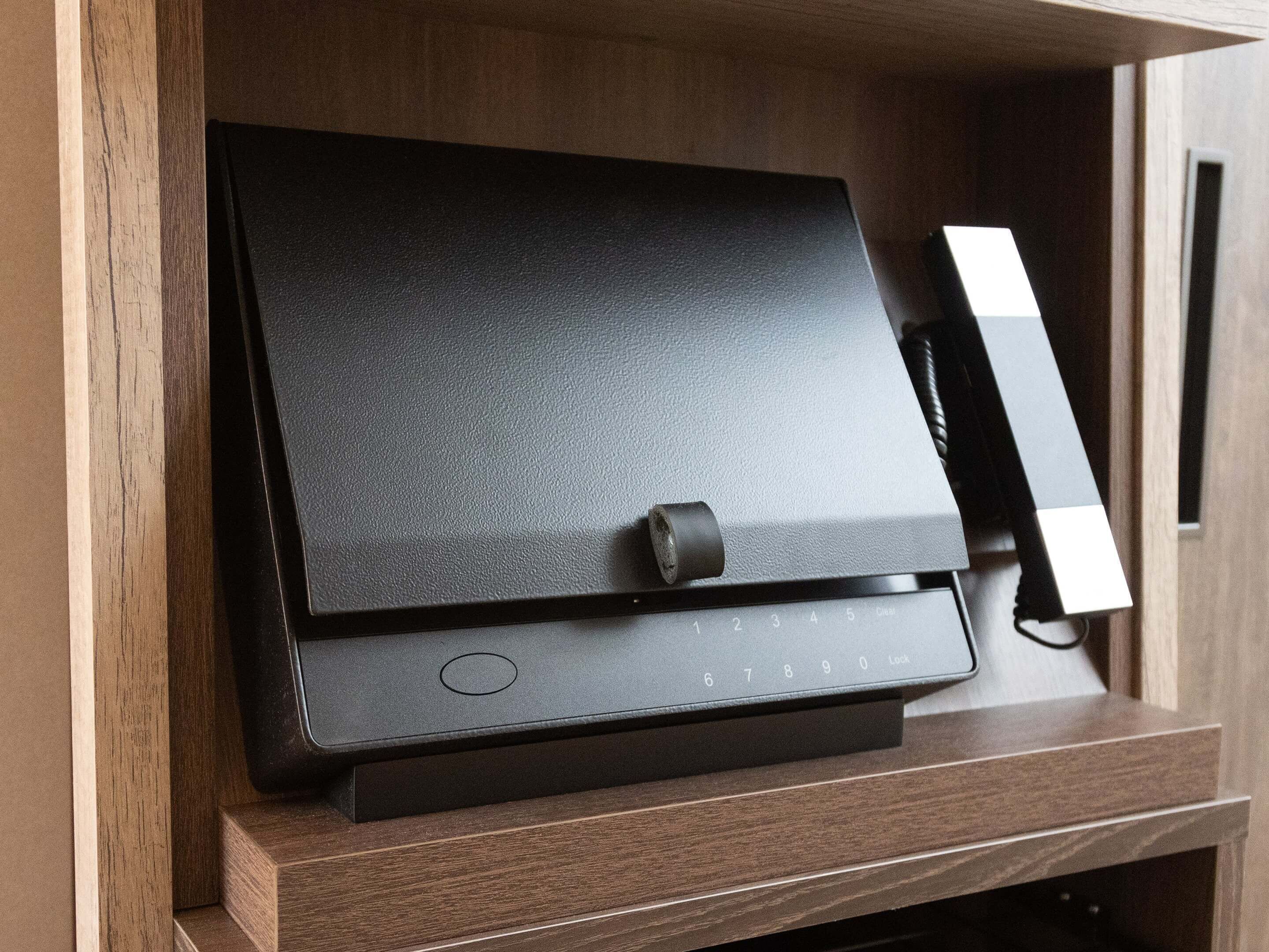 A black electronic device with a keypad and a small circular button, placed on a wooden surface.