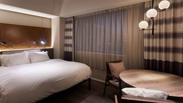 A hotel room with a large bed, a dining table, and a modern chandelier.